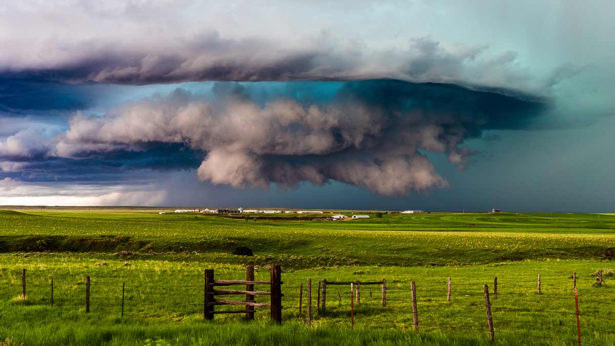 Supercell thunderstorm with dramatic clouds over a green grass field in eastern Montana.